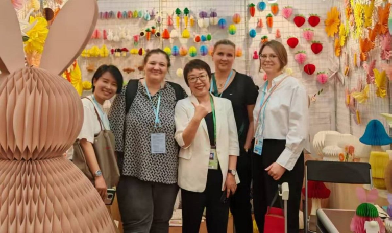 Founder Anna Mei and clients at the trade show booth of Sunbeauty, with vibrant honeycomb paper bunny and flower decorations
