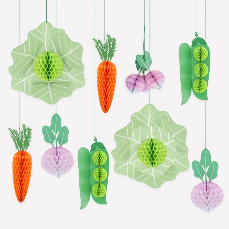 10 Giant Vegetable Decorations, showing orange honeycomb carrots, green honeycomb cabbages, purple honeycomb turnips, and pea pod decorations on a brown cardboard box with a scalloped white background.