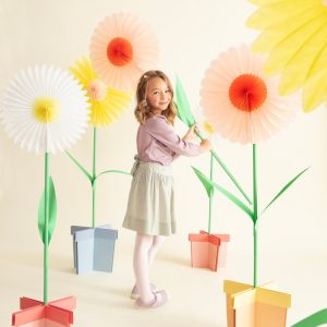 Child with giant pastel paper daisy party decorations
